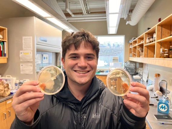 A UArizona student holding two petri dishes