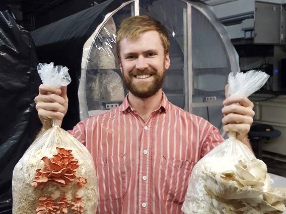 a students holds bags of mushrooms after harvest